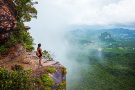 Woman standing on top of a mountain and looking out over the jungle
